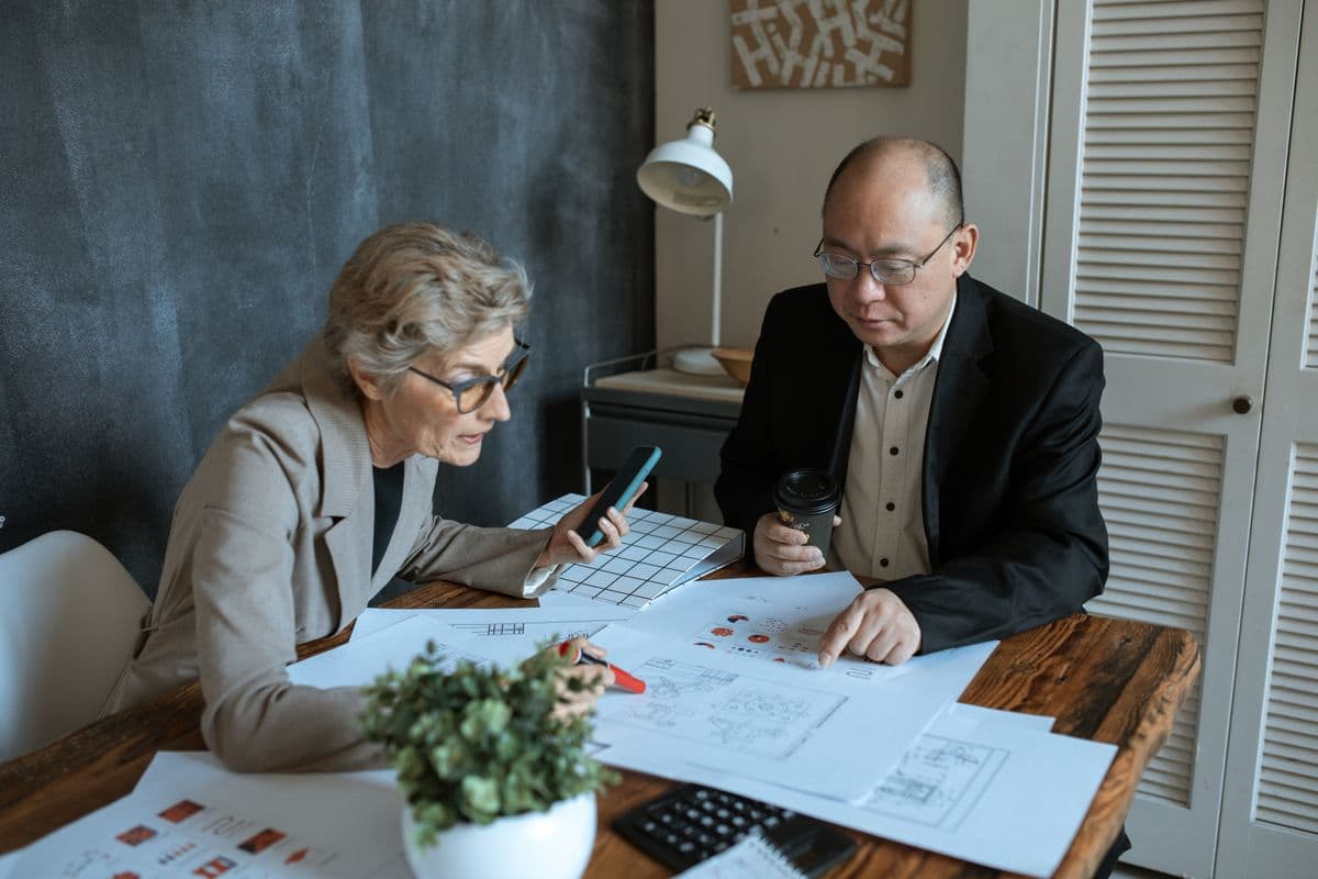 Two professionals reviewing paper claim documents at a desk