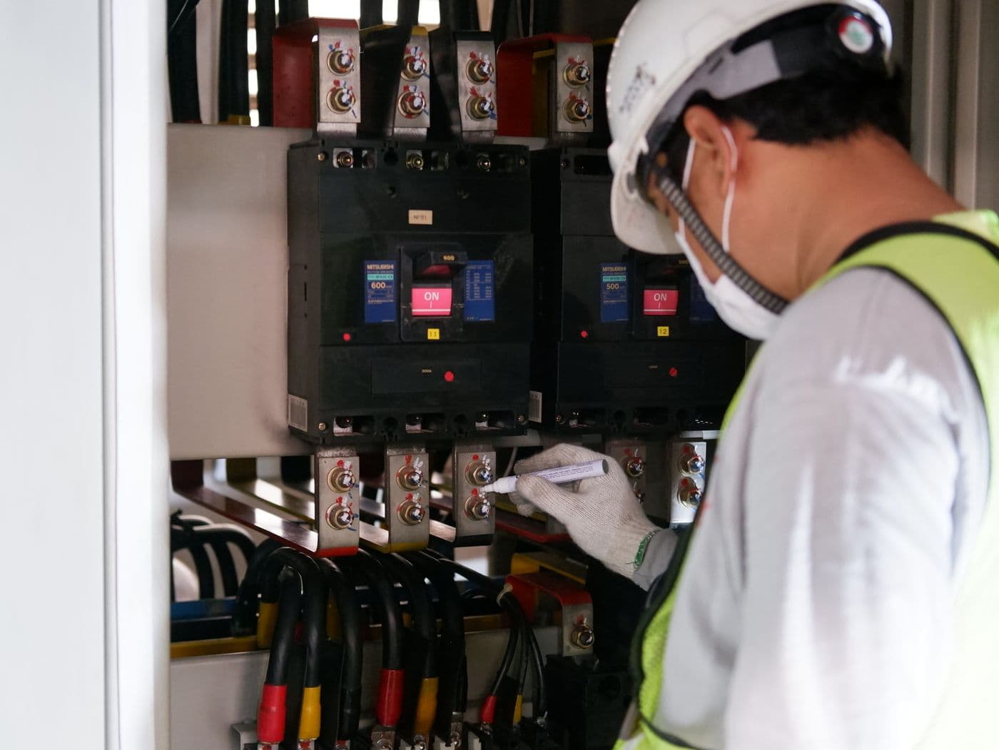 A technician inspecting an industrial electrical switchgear panel